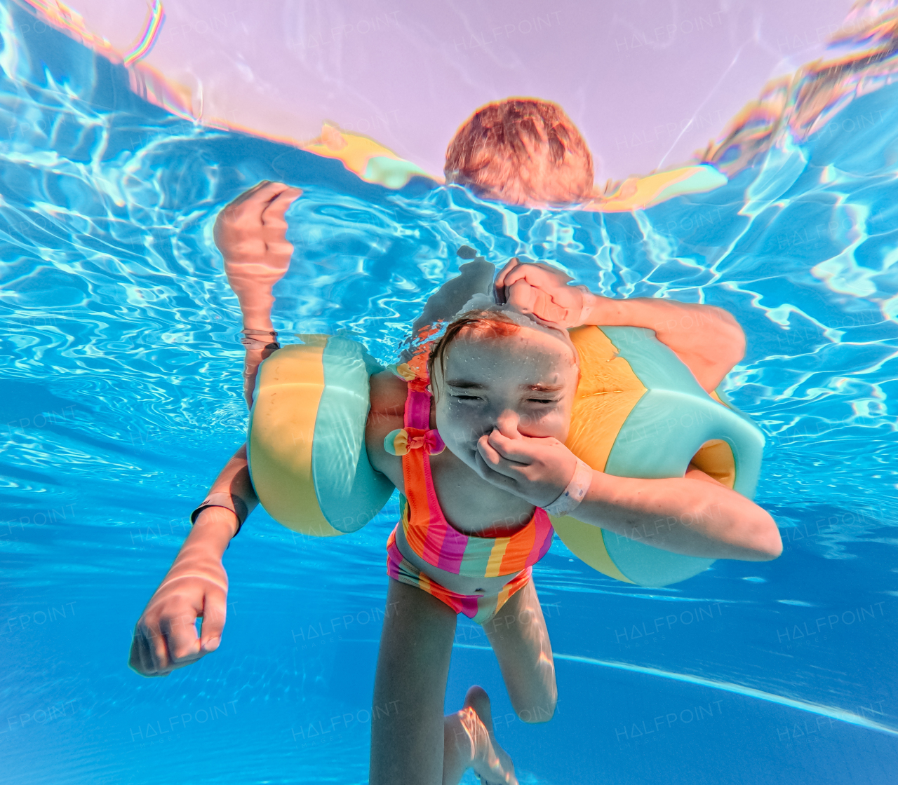 Little girl in swimsuit diving in a swimming pool.