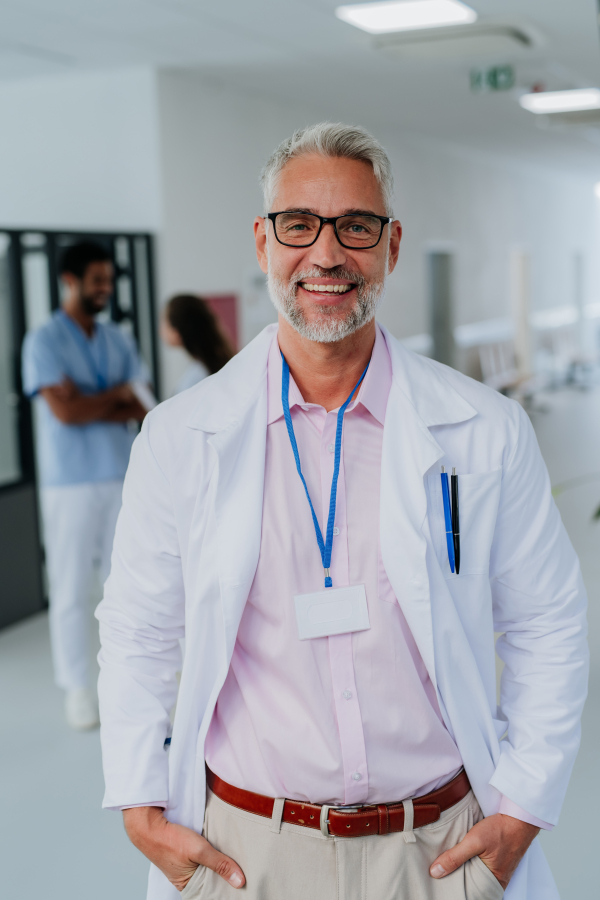 Portrait of mature doctor at a hospital corridor.