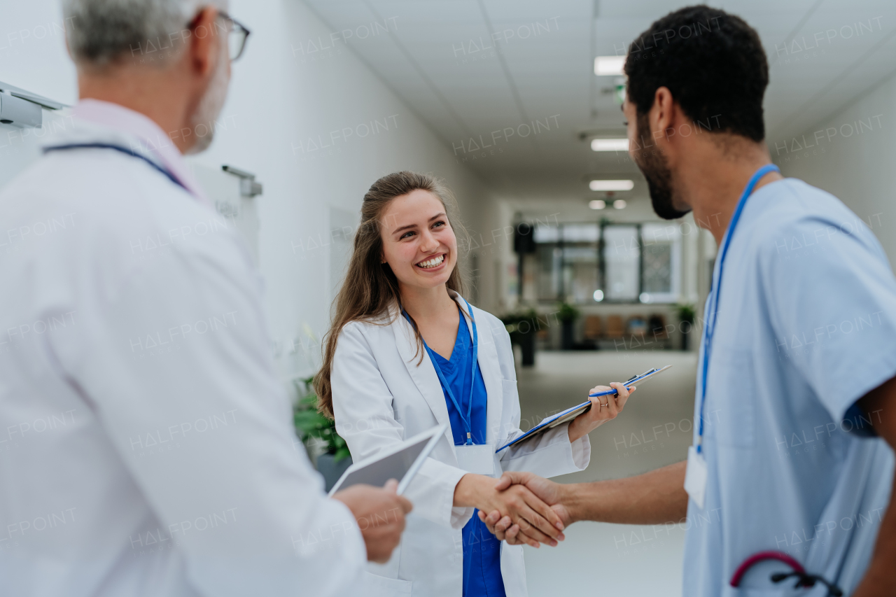 Close-up of doctors shaking hands at a hospital corridor.