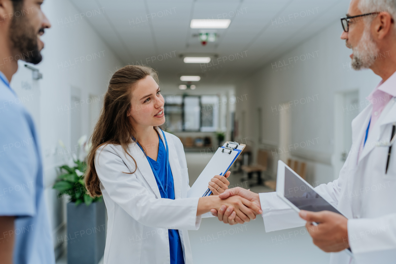 Close-up of doctors shaking hands at a hospital corridor.