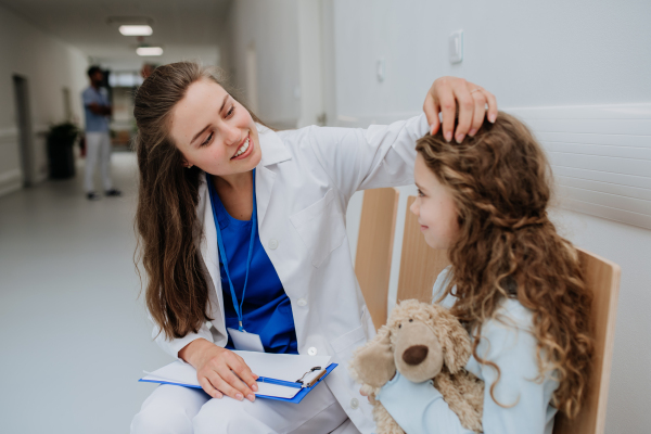 Young doctor playing with his little patient at pediatrics corridor.