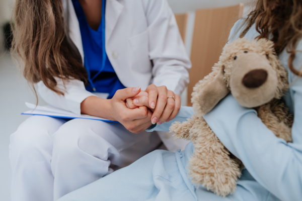 Close-up of doctor consoling little patient at pediatrics corridor.