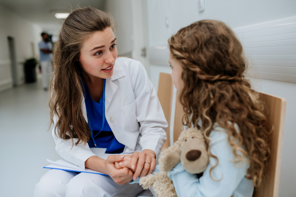 Young doctor talkingwith his little patient at pediatrics corridor.