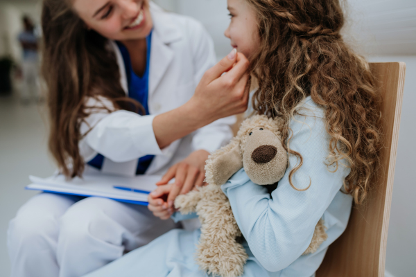 Young doctor playing with his little patient at pediatrics corridor.