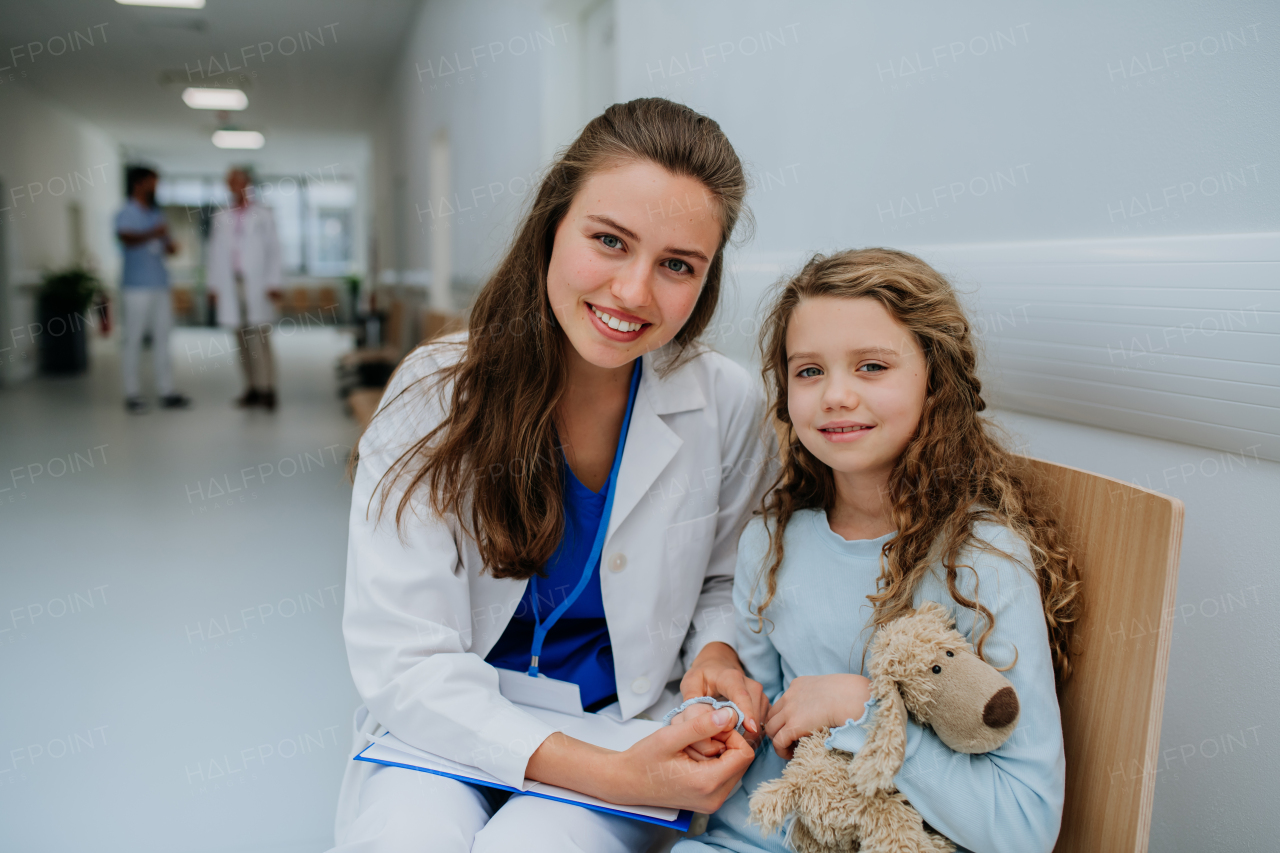 Portrait of young doctor with his little patient at pediatrics corridor.