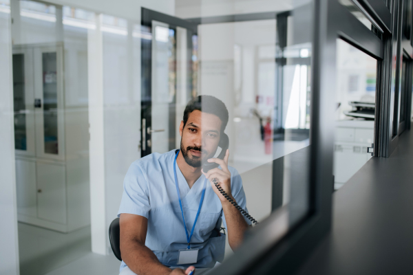 Young multiracial nurse sitting at reception and calling.