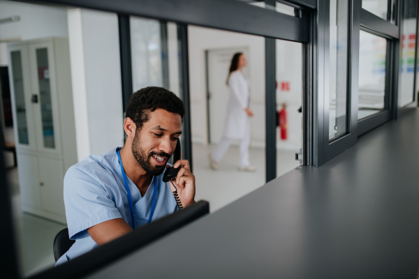 Young multiracial nurse sitting at reception and calling.