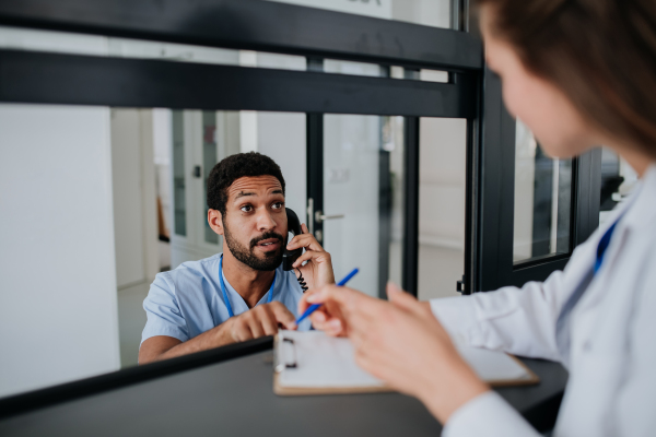 Young doctor talking with her colleague at hospital reception.