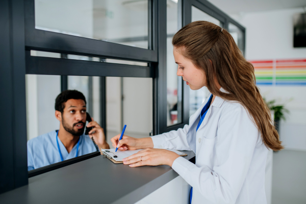 Young doctor talking with her colleague at hospital reception.