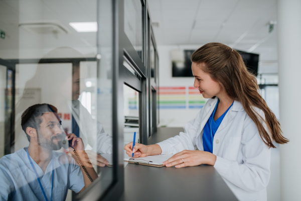 Young doctor talking with her colleague at hospital reception.