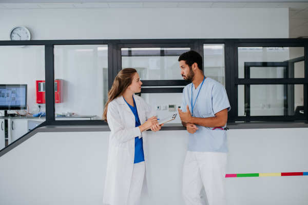 Young doctor talking with her colleague at hospital reception.