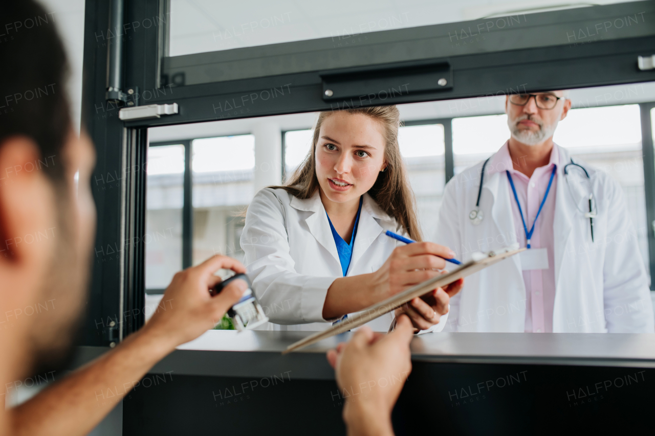 Young doctor talking with her colleague at hospital reception.