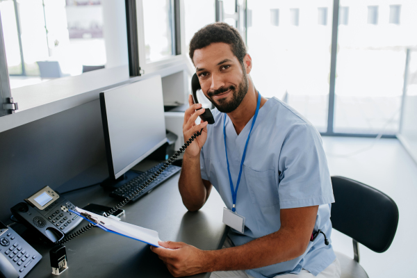 Portrait of young multiracial doctor sitting in his office and calling.