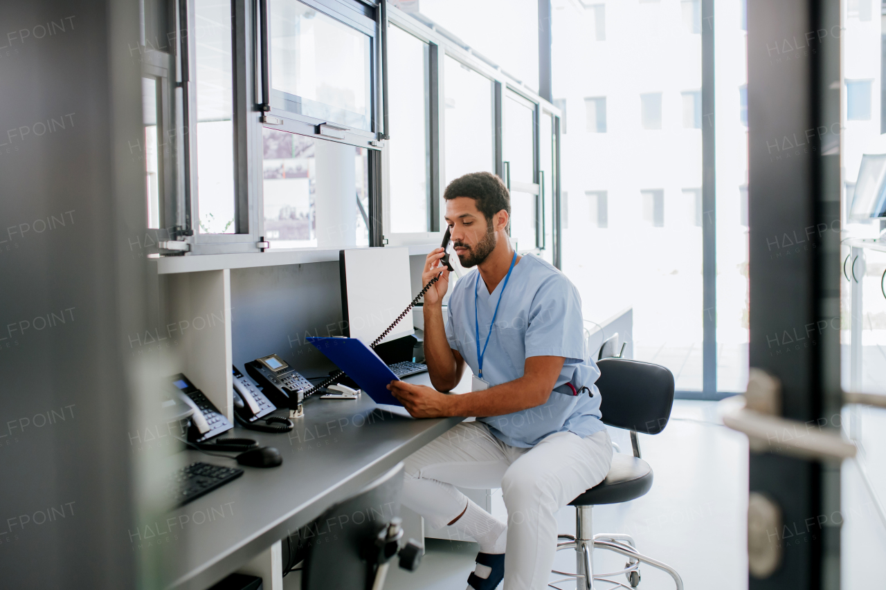 Young multiracial doctor sitting in his office and calling.