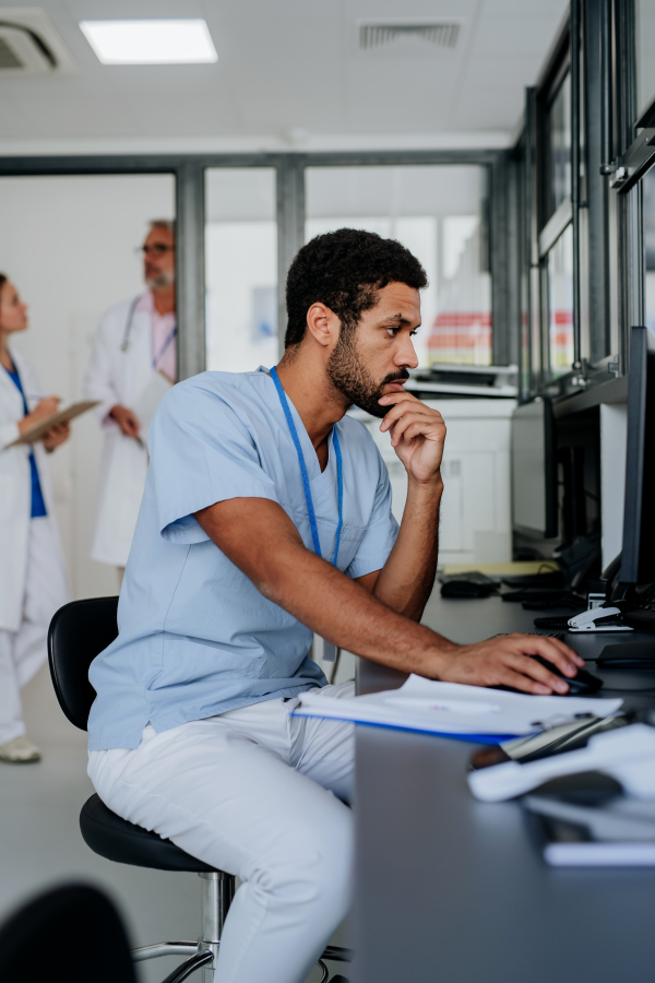 Portrait of young doctor working on computer in the hospital office.