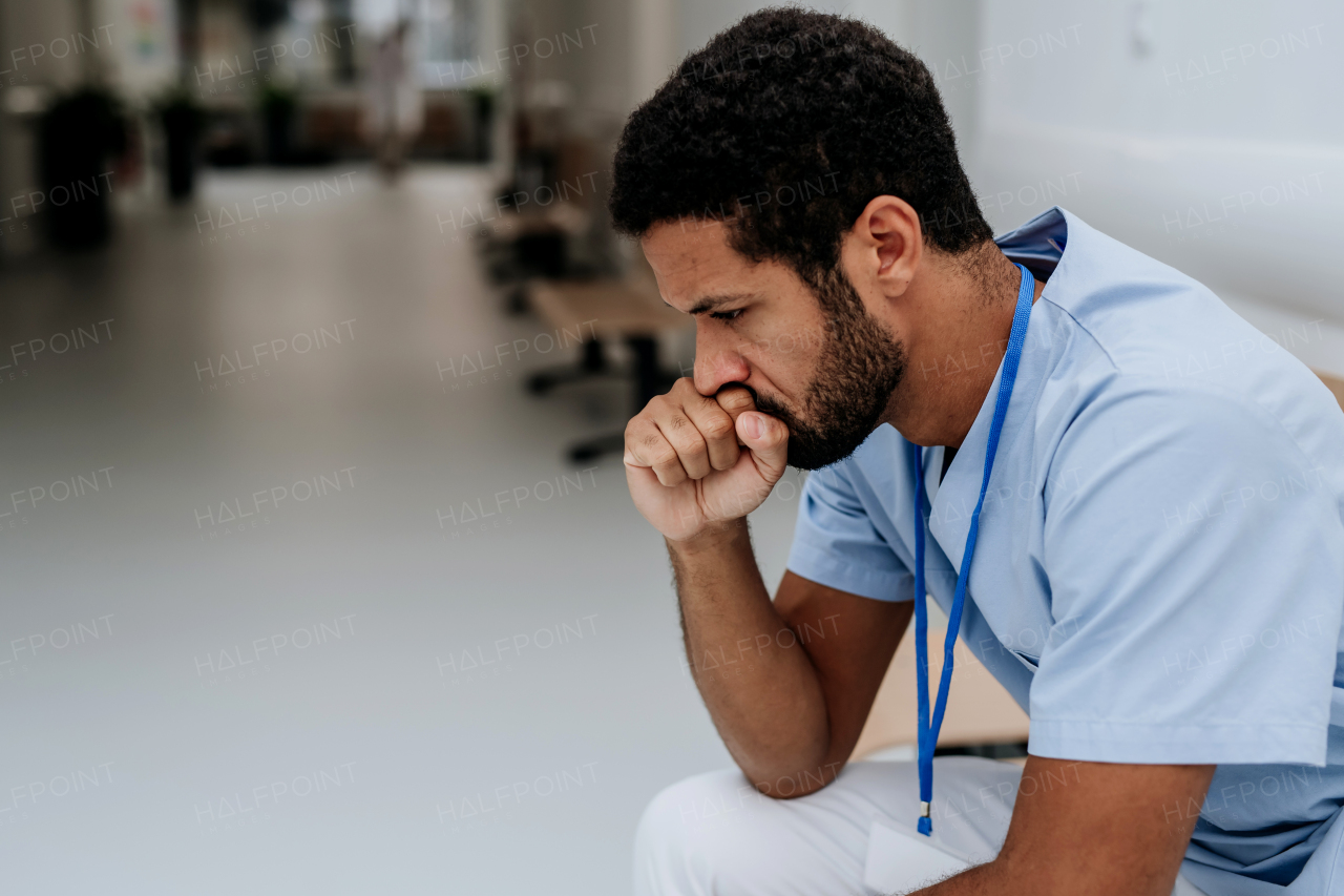 Young distressed doctor sitting at a hospital corridor floor.