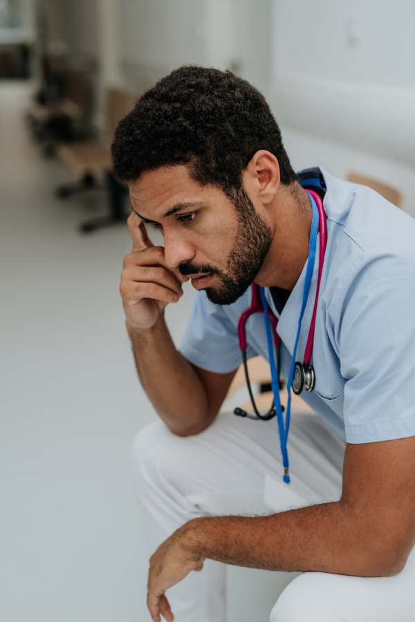 High angle view of tired doctor, sitting at a hospital corridor.