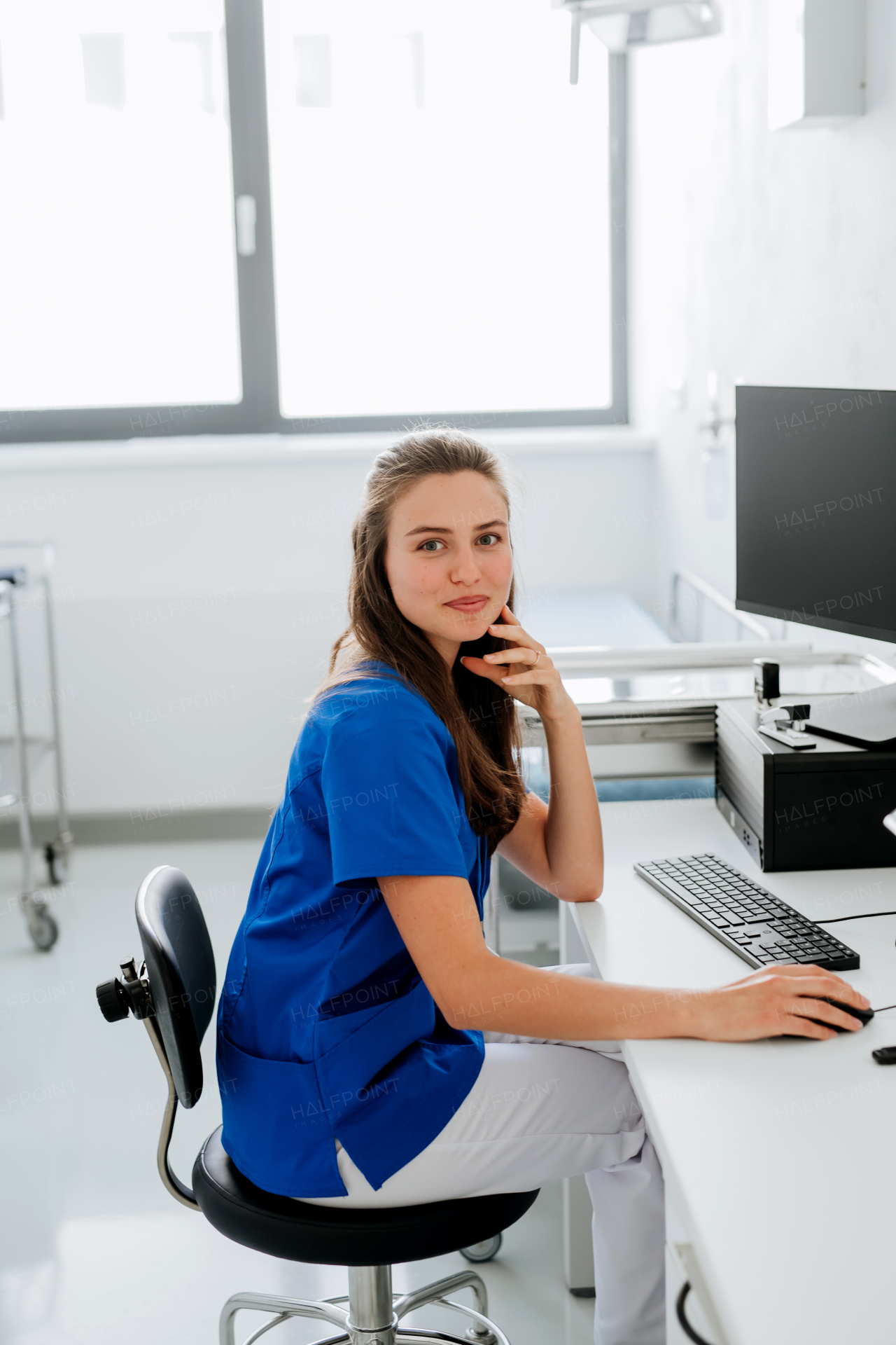 Young woman doctor sitting at a hospital office desk.