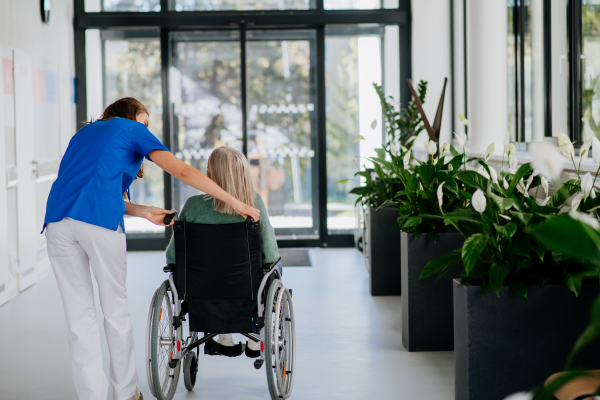 Young woman doctor taking care of senior woman at a wheelchair.