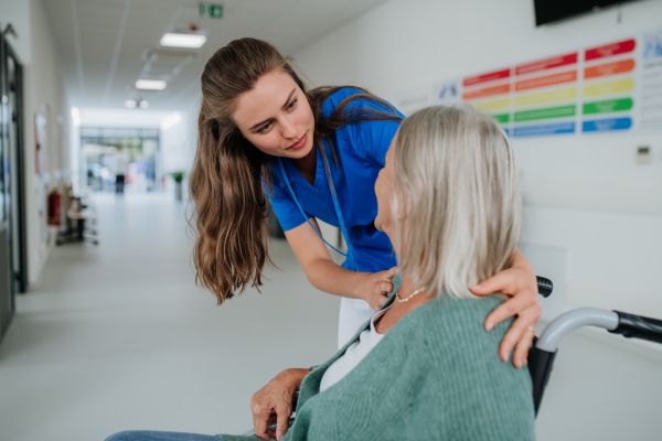 Young woman doctor taking care of senior woman at a wheelchair.