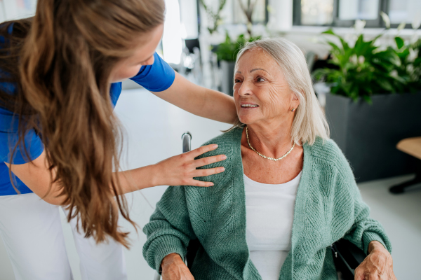 Young woman doctor taking care of senior woman at a wheelchair.