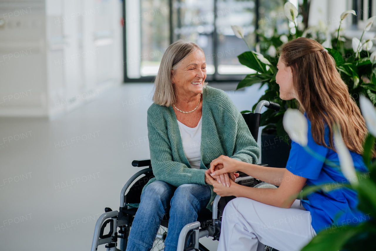 Young woman doctor taking care of senior woman at a wheelchair.