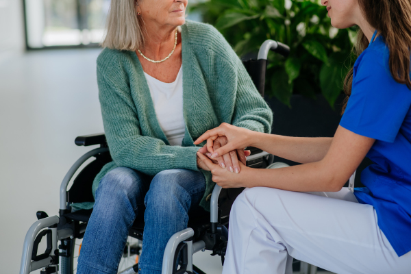 Close-up of woman doctor consoling of senior woman at a wheelchair.