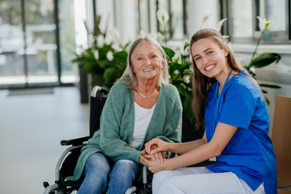 Young woman doctor taking care of senior woman at a wheelchair.