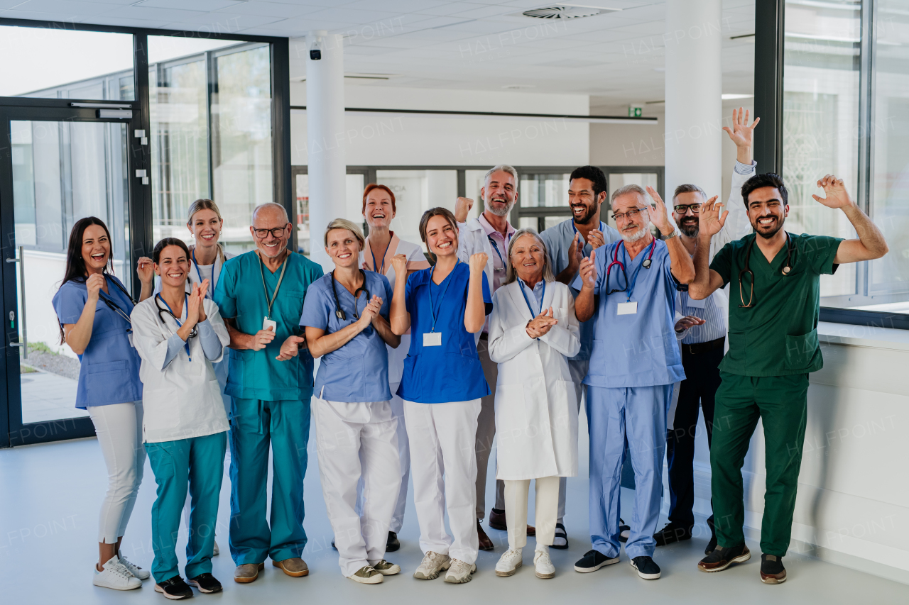 Portrait of happy doctors, nurses and other medical staff clapping, in a hospital.