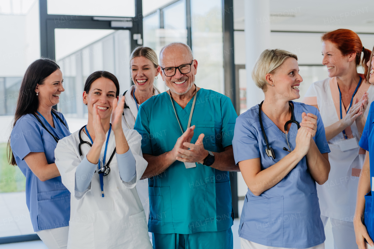 Portrait of happy doctors, nurses and other medical staff clapping, in a hospital.