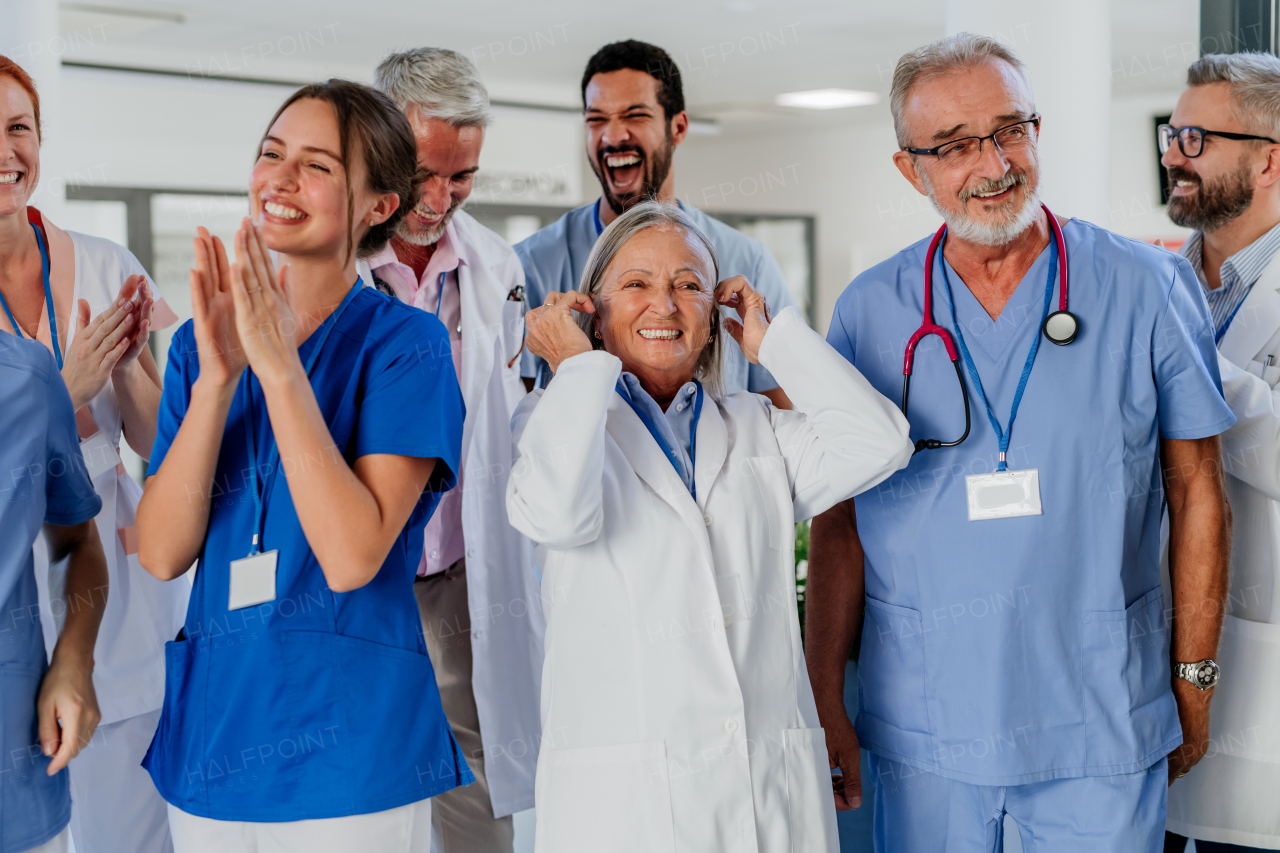 Portrait of happy doctors, nurses and other medical staff clapping, in a hospital.