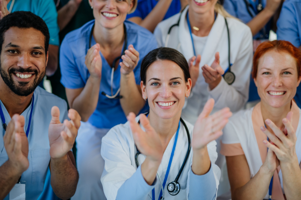 Portrait of happy doctors, nurses and other medical staff clapping, in a hospital.