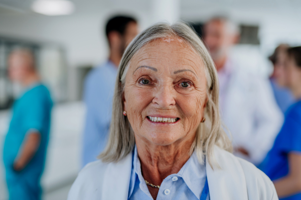 Portrait of elderly doctor at a hospital corridor.