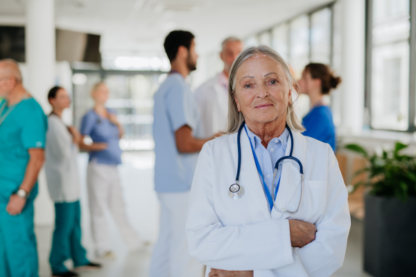 Portrait of elderly doctor at a hospital corridor.