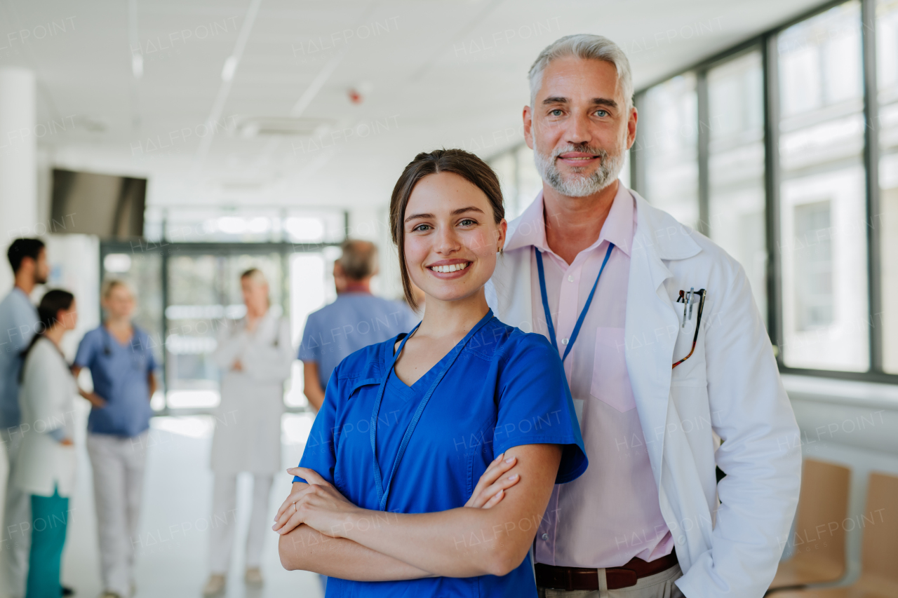 Portrait of elderly doctor with his younger colleague at a hospital corridor. Health care concept.