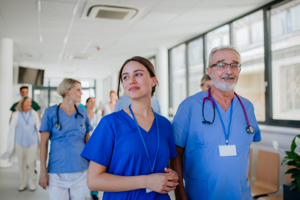 Portrait of elderly doctor with his younger colleague at a hospital corridor. Health care concept.