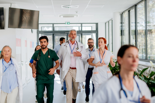 Young stressed doctors running at a hospital corridor.