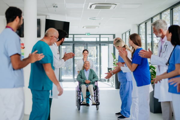 Medical staff clapping to patient who recovered from a serious illness.