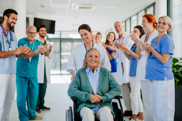 Medical staff clapping to patient who recovered from a serious illness.