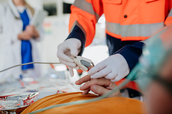 Close-up of rescuers taking care of patient from ambulance, giving him an EKG machine.