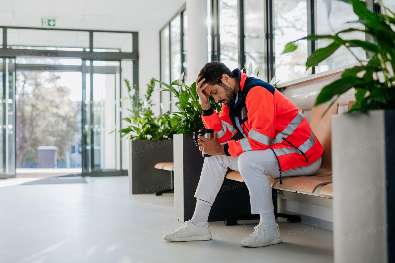 Young distressed rescuer sitting at a hospital corridor floor.