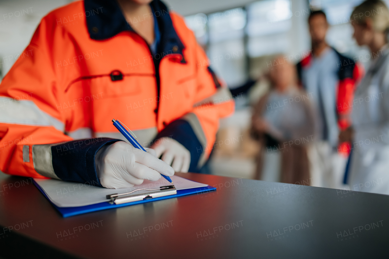 Close-up of rescuer filling out paper forms at hospital corridor.