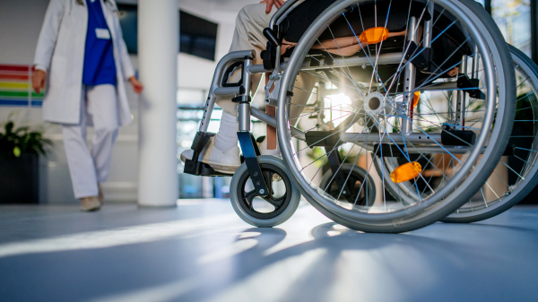 Close-up of wheelchair with senior woman at a hospital corridor.