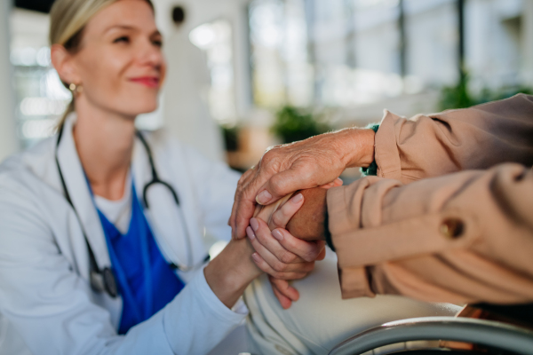 Close-up of young doctor holding hands of patient, consoling her.