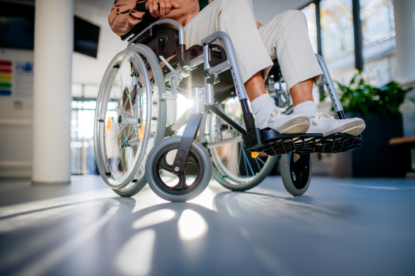 Close-up of wheelchair with senior woman at a hospital corridor.