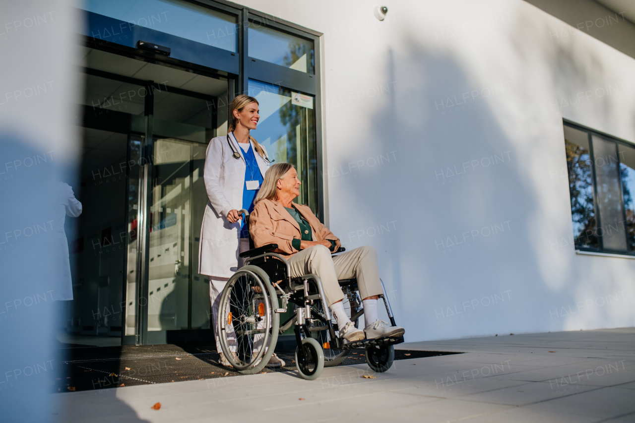 Young woman doctor taking care of senior woman at a wheelchair.