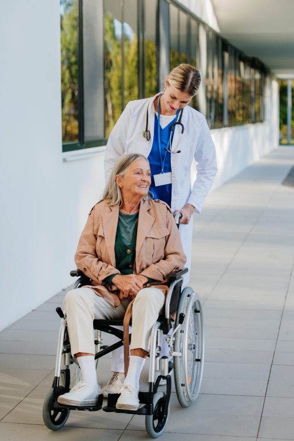 Young woman doctor taking care of senior woman at a wheelchair.