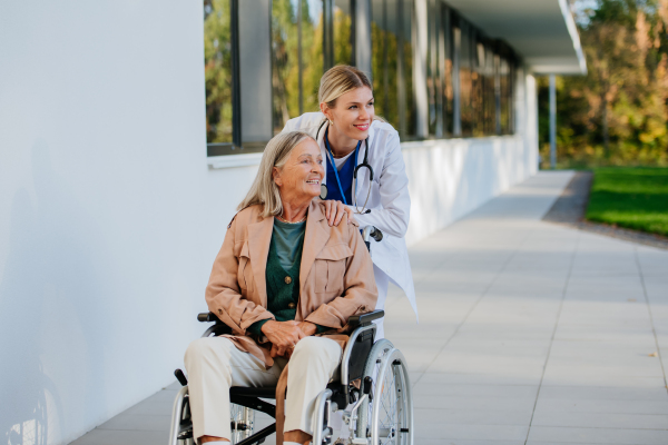 Young woman doctor taking care of senior woman at a wheelchair.