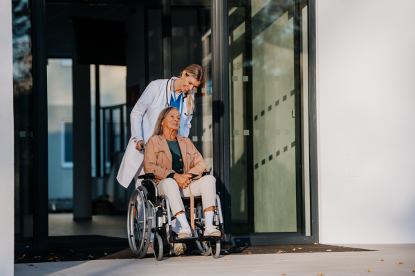 Young woman doctor taking care of senior woman at a wheelchair.