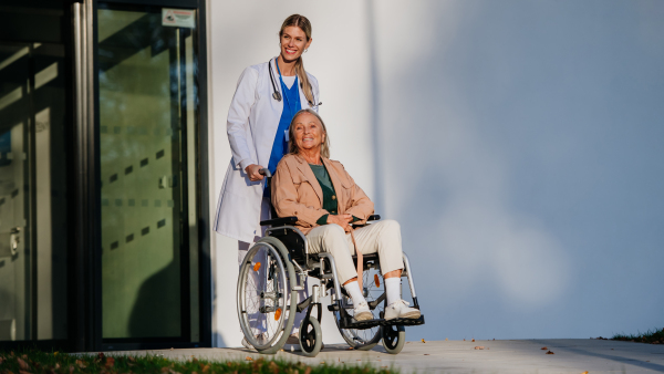 Young woman doctor taking care of senior woman at a wheelchair.